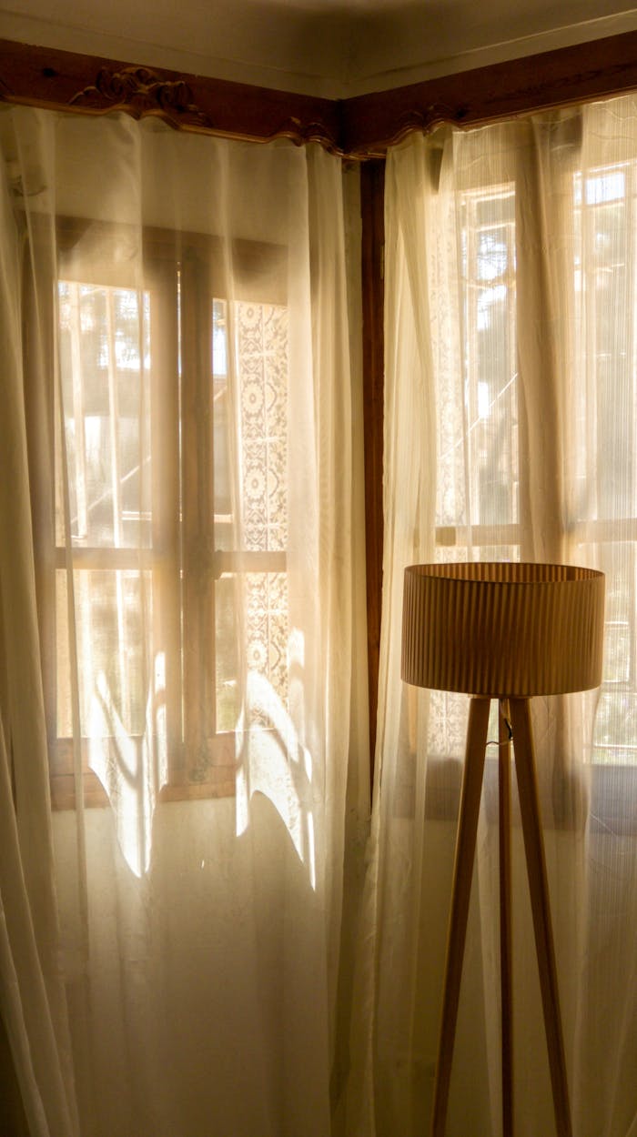 Warmly lit room featuring a vintage lamp and sheer curtains, exuding a cozy ambiance.